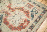 Distressed Sivas carpet corner displaying teal, red, and ivory curvilinear motifs with abrash.