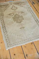 Distressed vintage Oushak rug's low pile surface and antique ivory zig-zag chevron border.