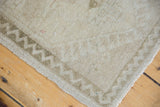 Distressed Oushak rug detail: low antique ivory pile and pale coffee zig-zag border.