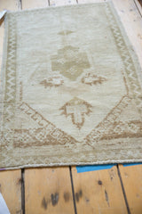 Fully secured end of the distressed vintage Oushak rug with low pile and antique ivory hues.
