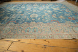 Distressed Tabriz rug detail: sky blue field, scrolling vinery, palmettes, and pale blush border.