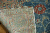 Distressed blue pile with red floral motif, revealing the intricate hand-knotted foundation and fringe.
