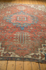 Corner of antique Serapi carpet with madder red, blue geometric motifs, and pile wear.