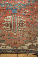 Antique Serapi carpet close-up, highlighting worn geometric patterns in rust red and muted blue tones.
