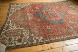 Antique fragmented Serapi carpet, showcasing bold geometric patterns in madder red and blue.
