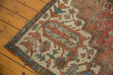 Close-up of an antique Serapi rug corner with rust red, sky blue, and beige geometric motifs.