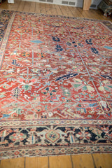 Vintage Heriz rug with dense geometric patterns in cherry red, navy, and ivory.