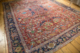 Vintage Heriz carpet: navy geometric border, cherry red field with intricate rectilinear patterns, and wear.