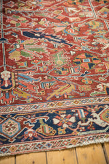 Detailed corner of vintage Heriz rug: cherry red field, geometric navy border, and fringe.