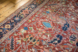 Geometric rectilinear drawing, cherry red field, navy border, and areas of wear on this vintage Heriz rug.