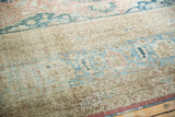 Distressed pile texture with visible foundation, showing muted pale blue and apricot patterns on beige.
