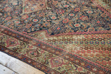 Antique Fereghan rug corner with diagonal floral spandrel and navy Herati pattern.