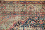 Antique Fereghan carpet corner with diagonal floral, Herati motifs in navy, blush, green, ivory.