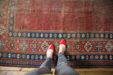 Antique Caucasian rug's madder red field, aged texture, and indigo blue pawn motif borders.