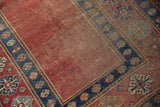 Antique Caucasian rug corner: madder red field, indigo border, and pawn motif.