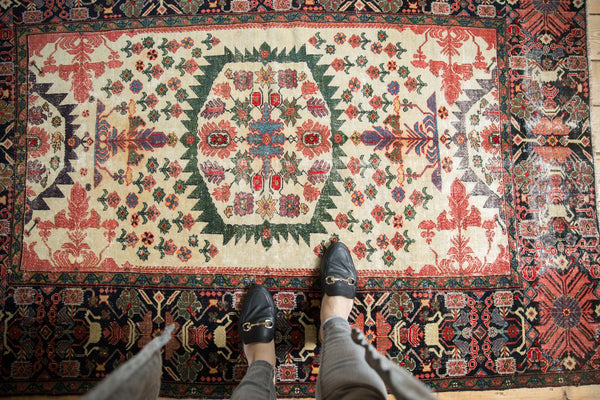 Antique Farahan Sarouk rug showing the serrated medallion, floral field, and intricately worn wide border.
