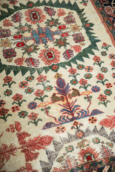 Antique Farahan Sarouk rug close-up showing the serrated green medallion and potted tree of life design.