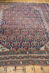 Vintage Shiraz carpet: intricate lower border, navy and brick red plant designs, and visible pile wear.