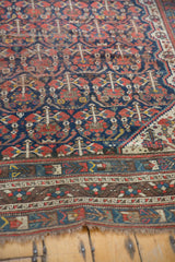 Vintage Shiraz carpet showing lower geometric borders and exposed foundation at the edge.
