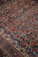 Germinating plant design, serpents, and animals on a navy and red Vintage Shiraz rug.