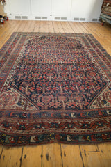Vintage Shiraz carpet featuring geometric borders in navy blue, brick red, ivory, with visible edge wear.