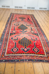 Angled view of an antique hand-knotted Karabagh runner's tree motif, birds, and faded red field.