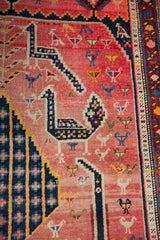 Antique Karabagh rug detail: prominent navy bird with animal figures on faded red.