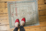Corner of a distressed vintage Oushak rug, featuring seafoam green and terra cotta geometric border.