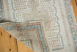Distressed Oushak rug corner revealing hand-knotted back, original multi-color selvages.