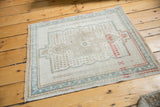 Distressed Oushak rug lower corner, with seafoam green vine border and textured ivory fringe.