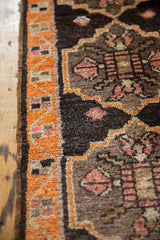 Geometric tangerine border and charcoal field motifs on a vintage Oushak rug.