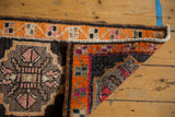 Folded corner of a Turkish Oushak rug, displaying tangerine border, geometric blush and charcoal motifs.