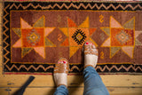 Vintage Oushak rug showing oversized saffron starbursts and nuanced zig-zag border.