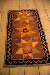 Vintage Oushak rug corner showing geometric starburst, charcoal zigzag border, and thick pile.
