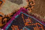 Vibrant magenta-bound edge of vintage Oushak rug with teal trim and tangerine patterned pile.