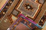 Vintage Oushak rug's folded corner shows hand-knotted weave, fuchsia fringe, and orange patterns.