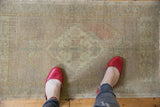 Distressed Oushak rug with faded ivory diamond medallion, sand, and blush tones.