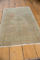 Distressed Oushak rug showing worn pile texture and delicate fringe.