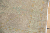 Textured pile of a distressed Oushak rug, showing even wear, original selvage, and muted floral pattern.