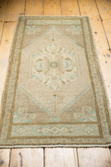 Vintage Oushak rug end finial detail, distressed pile texture, mint green floral motifs.