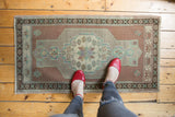 Distressed Oushak rug with pale copper, ivory, and mint green medallion underfoot.