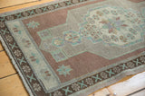 Distressed Oushak rug corner, even wear, pale copper, mint starburst, intact selvage.