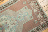 Distressed Oushak rug pile with geometric motifs in mint, lavender, and copper-bronze.