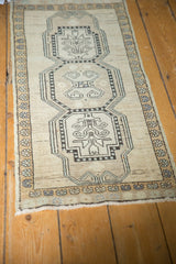 Fringed corner of vintage distressed Oushak rug with neutral tones and geometric medallion detail.