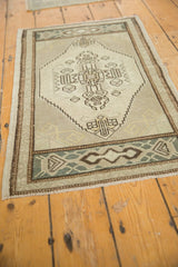 Distressed Oushak rug corner, geometric motifs, time-softened ivory, and coffee brown border.
