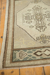 Vintage distressed Oushak rug corner, showing low pile and geometric motifs in beige, silver, and chocolate.