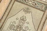 Close-up of distressed Oushak rug with worn beige pile and chocolate brown geometric motifs.