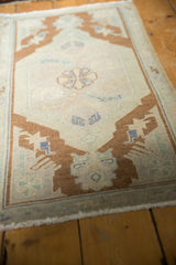 Expressive bronze leaf motif on a corner of the vintage Oushak mat, with even wear.