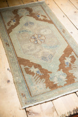Distressed Oushak rug mat corner with bronze pile, ivory tones, even wear, and fringe.