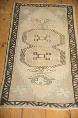 Distressed Oushak rug corner showing worn pile, chocolate border, seafoam plant element.
